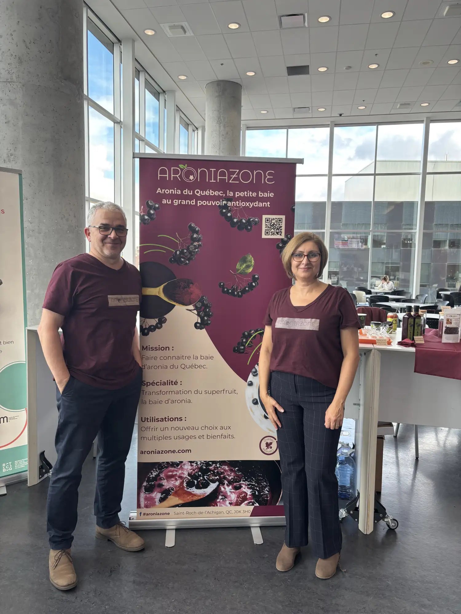 Bannière promotionnelle pour l'aroniazone maroon mettant en vedette des baies d'aronia noires et un design de cuillère.